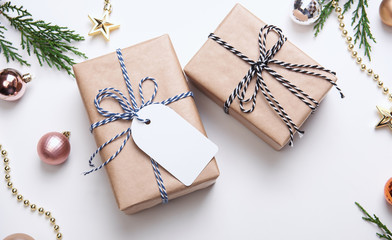 Christmas gift box with paper tag and christmas decorations on white background. winter, new year concept. Flat lay, top view, copy space.