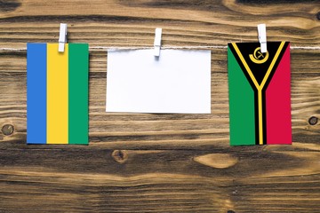 Hanging flags of Gabon and Vanuatu attached to rope with clothes pins with copy space on white note...
