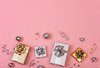 Obraz na płótnie Canvas Christmas composition with decorations and gift box with golden bows and star confetti on pink pastel background. winter, new year concept. Flat lay, top view, copy space.