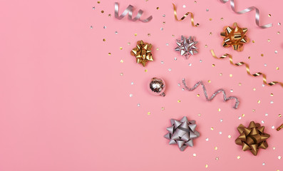 Christmas composition with decorations and  golden bows and star confetti on pink pastel background. winter, new year concept. Flat lay, top view, copy space.