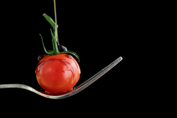 Styling food on a fork with a single tomato, mozzarella ball, basil, balsamic vinegar