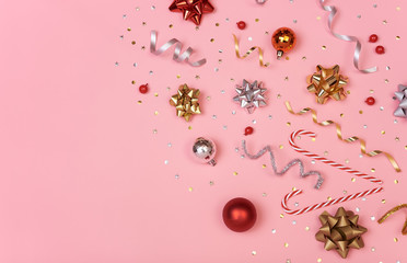 Christmas composition with decorations and  golden bows and star confetti on pink pastel background. winter, new year concept. Flat lay, top view, copy space.