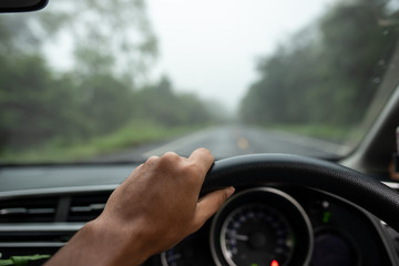 View on the dashboard of the truck driving.The driver is holding the steering wheel. Forest road is in front of the car