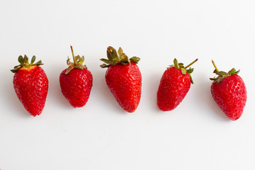 row of red strawberries berries on white background