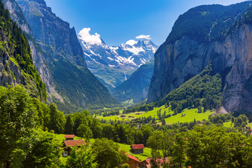 Fototapeta premium Lauterbrunnen valley, waterfall and the Lauterbrunnen Wall in Swiss Alps, Switzerland. Eiger, Monch and Jungfrau mountains in the background.