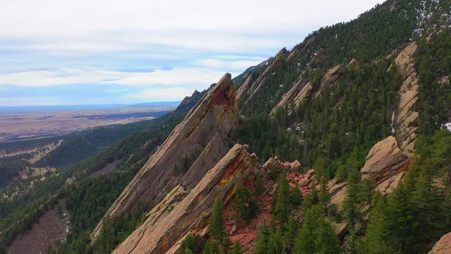 Aerial: Drone reversing over friends standing on rocky mountain peak, scenic view of landscape against sky - Boulder, Colorado