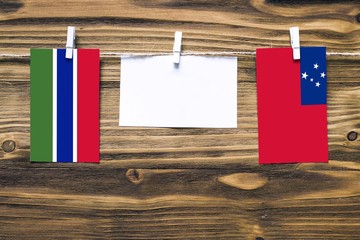 Hanging flags of Gambia and Samoa attached to rope with clothes pins with copy space on white note...