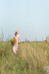 girl with a basket of flowers and a straw hat in a summer field