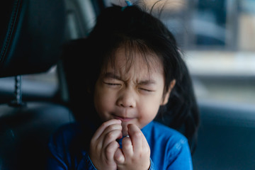 little asian girl with sour gesture face on the car when she eat lemon slice.