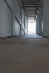 Low angle perspective view of dim concrete building space with columns