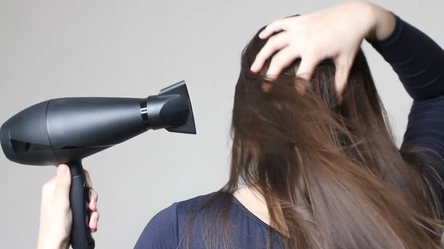 Close up video of  Woman drying hair using black hair dryer