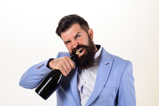 Sexy male model pulls out cork with teeth with bottle of wine. Brutal handsome man opens his teeth bottle of champagne. Champagne or wine bottle. Bearded man trying to open bottle of wine. Bad habits.