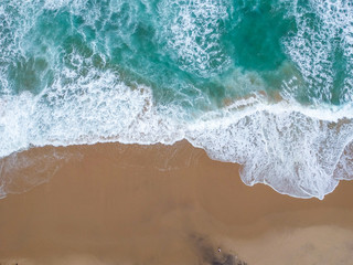 Sand beach aerial, top view of a beautiful sandy beach aerial shot with the blue waves rolling into the shore
