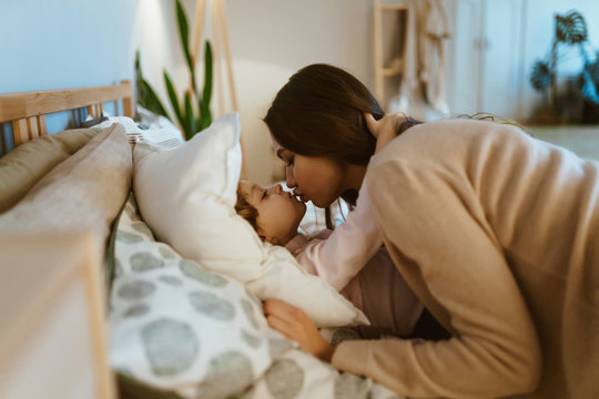 mom kisses daughter before going to bed