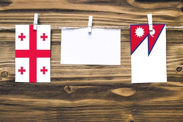 Hanging flags of Georgia and Nepal attached to rope with clothes pins with copy space on white note...