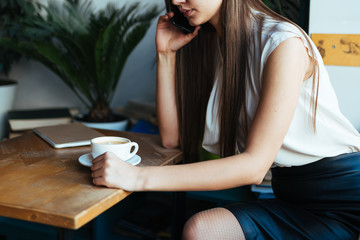 office manager calls and drinks coffee at a table