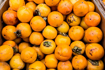 Fresh organic persimmon on the farmers market. Autumn harvest of orange persimmons. Healthy vegan food.