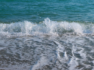Closeup of Mediterranean Sea wave with surf and foam. High shutter speed fixation, front view, low angle 