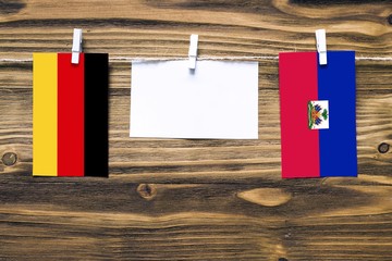 Hanging flags of Germany and Haiti attached to rope with clothes pins with copy space on white note...