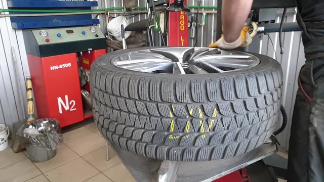 Assembly and disassembly of auto tires ; Mechanic in the workshop serviced the car wheels and mounted a new tire on the rim