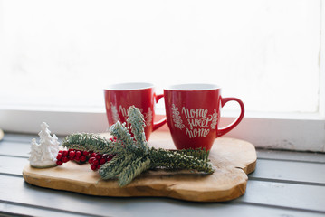 Two red mugs on a wooden tray on the windowsill, Christmas decor