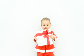 Little baby boy wear santa suit smile and open gift box with red bow on white background.Happy and excied boy child in santa suit holding gift box in the bed.