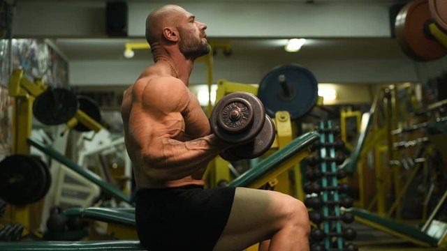 Handsome strong athletic man pumping up biceps muscles workout fitness and bodybuilding concept background - muscular bodybuilder fitness men doing arms exercises in gym naked torso