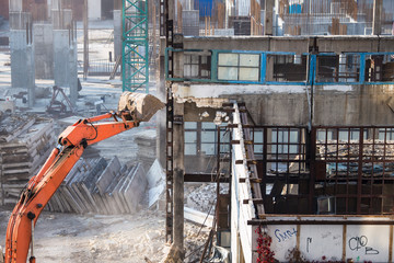 construction site, excavator bucket destroys an old building on site