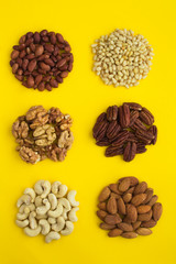 Set of different nuts  on the yellow  background. Top view. Closeup. Location vertical.