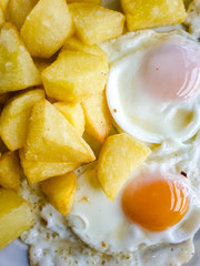 Zenith view of a typical Spanish homemade food, based on grilled eggs and fried potatoes in olive oil.