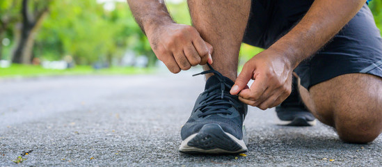 Male runner trying running shoes getting ready for run. Healthy workout woman jogging outdoors.