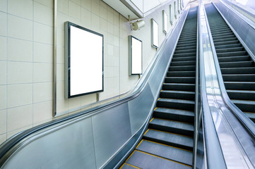 Fototapeta premium Blank billboard mock up on the wall beside the escalator at the subway station. Advertising concept