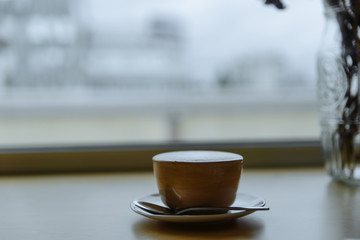 Cup of coffe with milk on a dark background. Hot latte or Cappuccino prepared with milk on a wooden table with copy space