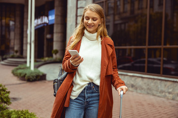 Joyful trendy young woman using her cellphone