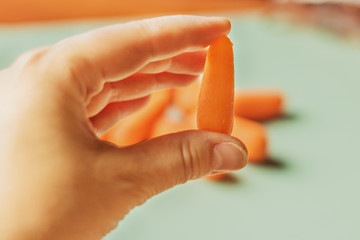 Small carrot in hand on green background