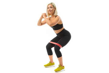 Sport caucasian girl do sports with elastic for fitness and shakes legs muscles isolated on white background