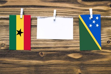 Hanging flags of Ghana and Solomon Islands attached to rope with clothes pins with copy space on...