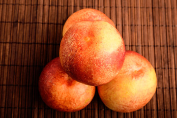 Four fresh ripe organic nectarines on a wooden brown table, top view or flat lay photo of healthy fruits