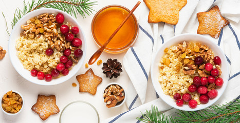 Tasty and healthy winter breakfast. Bulgur porridge with berries, walnut and honey on a light background, top view, flat lay. Winter food.