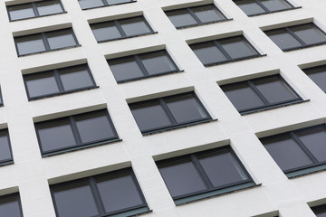 New apartment facade painted white smooth parget and dark black windows, diagonal view, ground view.
