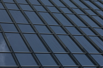 Fototapeta premium Angular view of glass building wall reflecting sky