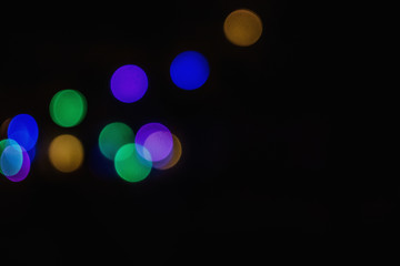 The blurred background of a Christmas garland on a black background is out of focus. Abstract Christmas background.
