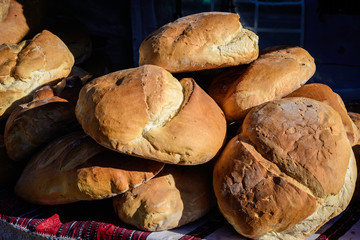 Fresh homemade whole-grain bread displayed for sale in a black plastic baskets at a street food market, selective focus