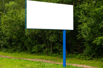 White empty billboard against green forest along road