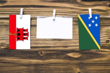 Hanging flags of Gibraltar and Solomon Islands attached to rope with clothes pins with copy space...