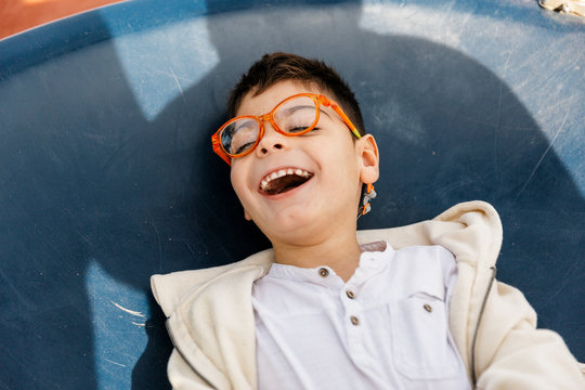ni&ntilde;o en el parque en columpio grande redondo balance&aacute;ndose y riendo . Ni&ntilde;o con pluri discapacidad.
