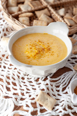 Pumpkin cream spiced with curry in a white bowl and some roasted pumpkin dice and croutons. Close Up
