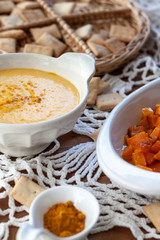 Pumpkin cream spiced with curry in a white bowl and some roasted pumpkin dice and croutons. Close Up