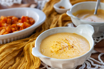 Pumpkin cream spiced with curry in a white bowl with roasted pumpkin and bread. Close Up