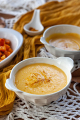 Pumpkin cream spiced with curry in a white bowl with roasted pumpkin and bread. Close Up